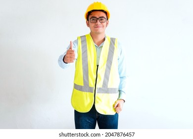 Young Latino Male, Engineer, Blue Checkered Shirt, Wearing Emergency Vest, Construction Helmet, Model With Arm Outstretched And Nod Of Approval.