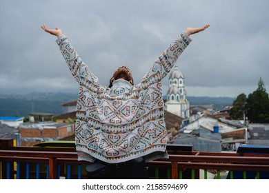 Young Latino Male Hippie Tourist Praying To The Pachamama In Filandia Quindío On A Terrace Overlooking The Church