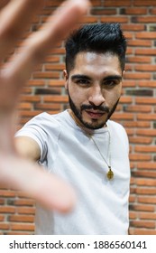 Young Latino Man Looking At Camera With Outstretched Hand