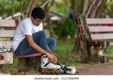 Young Latino Man Sitting Putting On Inline Skates 