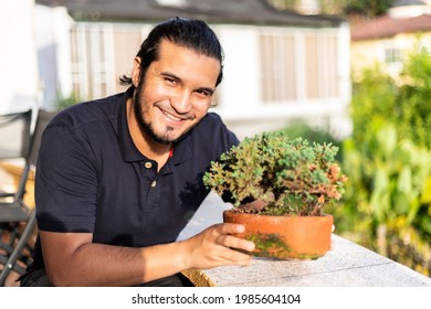 Young Latino Man Taking Care Of A Bonsai In A Clay Pot. New Normal