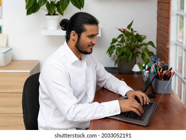 Young Latino Man Typing In Laptop In Home