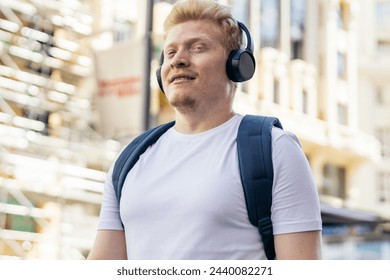 Young Latino man who is albino walking down the city street listening to music with headphones on a summer morning. - Powered by Shutterstock