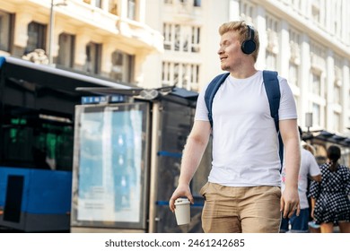 Young Latino man who is albino walking down the city street listening to music with headphones on a summer morning.  - Powered by Shutterstock