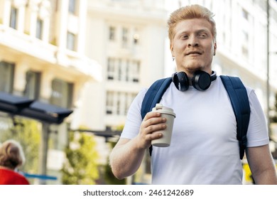 Young Latino man who is albino walking down the city street listening to music with headphones on a summer morning.  - Powered by Shutterstock