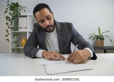 Young Latino Multiracial Businessman Signing Documents In His Office. Male Entrepreneur Preparing Before Business Meeting. Taking Notes. Business Concept.