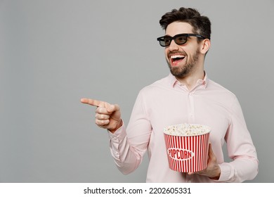 Young Laughing Smiling Cheerful Happy Man In 3d Glasses Watch Movie Film Hold Bucket Of Popcorn In Cinema Point Index Finger Aside On Workspace Area Isolated On Plain Grey Background Studio Portrait