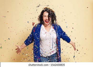 Young Laughing Woman In Confetti Celebrates. Yellow Background.