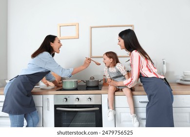 Young lesbian couple with adopted little girl cooking in kitchen - Powered by Shutterstock