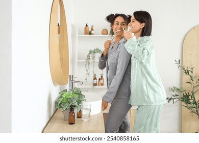 Young lesbian couple brushing teeth in bathroom - Powered by Shutterstock