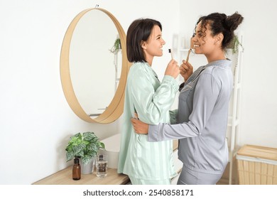 Young lesbian couple brushing teeth in bathroom - Powered by Shutterstock