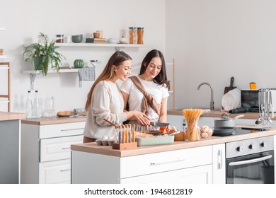 Young Lesbian Couple Cooking Dinner In Kitchen