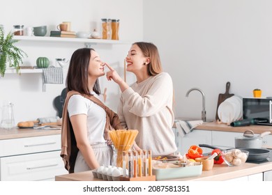 Young Lesbian Couple Cooking Dinner In Kitchen