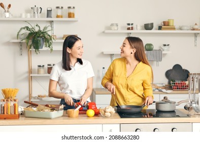 Young Lesbian Couple Cooking Dinner In Kitchen