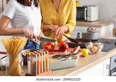 Young Lesbian Couple Cooking Dinner In Kitchen