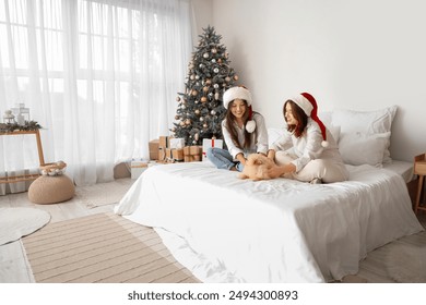 Young lesbian couple with dog in bedroom on Christmas eve - Powered by Shutterstock