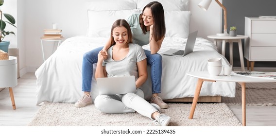 Young Lesbian Couple With Laptop In Bedroom