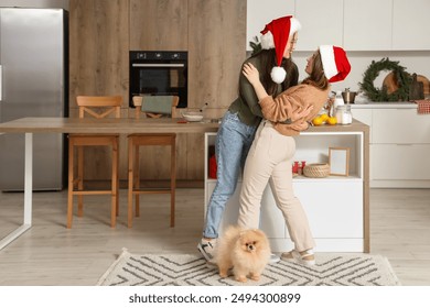 Young lesbian couple with Pomeranian dog dancing in kitchen on Christmas eve - Powered by Shutterstock