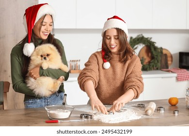 Young lesbian couple with Pomeranian dog making cookies in kitchen on Christmas eve - Powered by Shutterstock