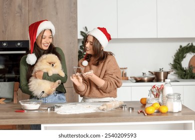 Young lesbian couple with Pomeranian dog making cookies in kitchen on Christmas eve - Powered by Shutterstock