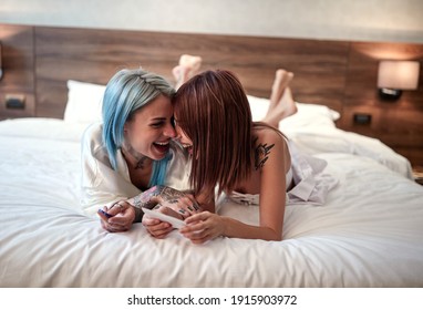 A young lesbian couple relaxing in the bed is excited about positive pregnancy test result. Love, pregnancy, lgbt, relationship