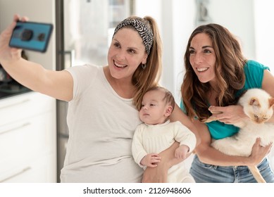 A Young Lesbian Couple With Their Baby And Cat Taking A Picture -gay Parents, Gay Marriage And Adoption Concept