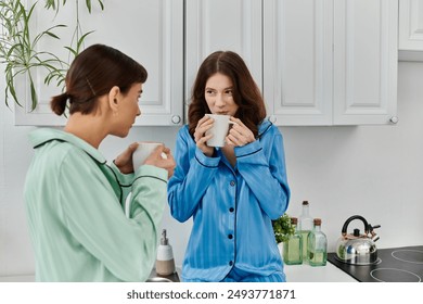 A young lesbian couple, wearing pajamas, enjoys a quiet morning together in the kitchen, sharing a warm beverage. - Powered by Shutterstock