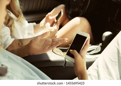 Young lesbian's couple preparing for vacation trip on the car in sunny day. Women sitting and ready for going to sea, riverside or ocean. Concept of relationship, love, summer, weekend, honeymoon.