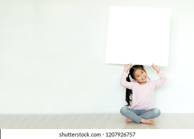 Young Little Asian Girl Or Kid Enjoy Holding Empty White Placard Board For Media Banner, Business Content Presentation, Mock Up Blank Sign For Message With Positive And Fun In Creative Design Concept.