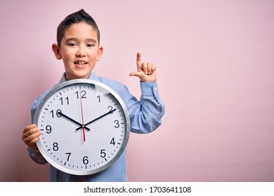 Young Little Boy Kid Holding Big Minute Clock Over Isolated Pink Background Surprised With An Idea Or Question Pointing Finger With Happy Face, Number One