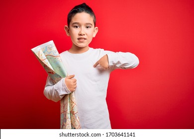 Young Little Boy Kid Looking At Turist City Destination Map Over Red Isolated Background With Surprise Face Pointing Finger To Himself