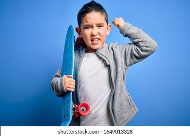 Young Little Boy Kid Skateboarder Holding Modern Skateboard Over Blue Isolated Background Annoyed And Frustrated Shouting With Anger, Crazy And Yelling With Raised Hand, Anger Concept