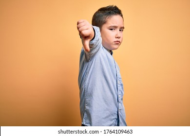 Young Little Boy Kid Wearing Elegant Shirt Standing Over Yellow Isolated Background Looking Unhappy And Angry Showing Rejection And Negative With Thumbs Down Gesture. Bad Expression.