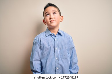 Young little boy kid wearing elegant shirt standing over isolated background smiling looking to the side and staring away thinking.