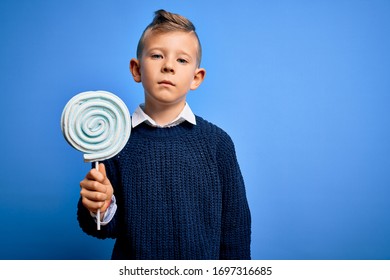 Young Little Caucasian Kid Eating Sweet Candy Lollipop Over Blue Isolated Background With A Confident Expression On Smart Face Thinking Serious