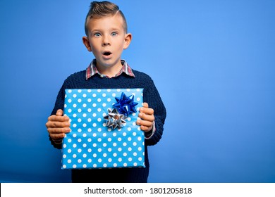 Young Little Caucasian Kid Holding Surprise Box As Birthday Or Christmas Present Scared In Shock With A Surprise Face, Afraid And Excited With Fear Expression