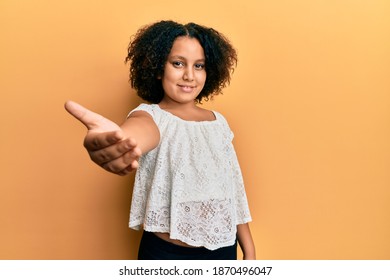 Young little girl with afro hair wearing casual clothes smiling friendly offering handshake as greeting and welcoming. successful business.  - Shutterstock ID 1870496047
