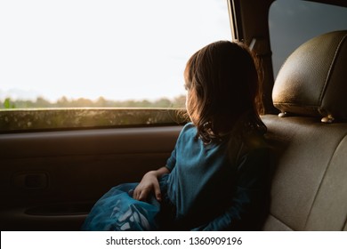 Young Little Girl Enjoying The Trip In Back Seat Looking Out The Window Of The Car