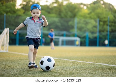 Young Little Kid Enjoying Happy Playing Football Soccer In City Park Hits The Ball Gives A Pass And Likes To Play In The Street Oblivious To People