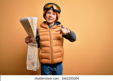 Young Little Kid Wearing Snow Glasses And Winter Coat Looking At Tourist Map With Surprise Face Pointing Finger To Himself