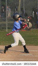 A Young Little League Batter Swings At A Pitch