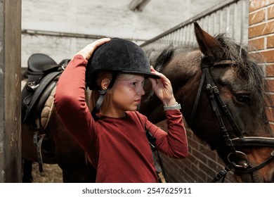 Young little teenager kid girl cleaning grooming chestnut horse back hair brush tool horse at stable ranch. Horse ride school farm life. Cute little blond girl kid care brown horse. Equine hobby work - Powered by Shutterstock