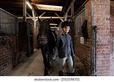 Young little teenager kid girl leading chestnut horse through stable ranch yard. Horse riding school exercise.  Cute little beginner blond girl kid near beautiful brown horse. Equine hobby or work - Powered by Shutterstock