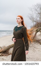 Young long hair redhead viking girl on the beach