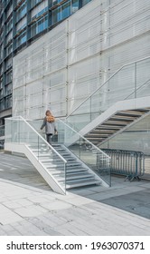 Young long hair woman in casual dress going up stair through a white urban staircase in a sunny day