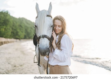 Young Long Hair Woman In White Shirt Riding White Horse On Seascape Background