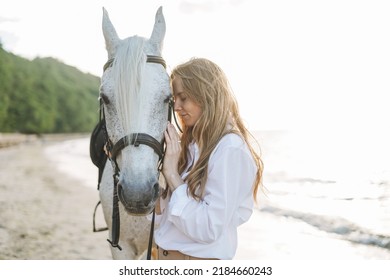 Young Long Hair Woman In White Shirt Riding White Horse On Seascape Background