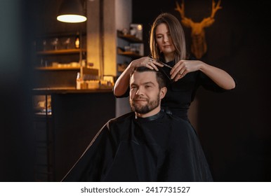 Young long haired female barber gently makes undercut hairstyle using scissors and comb bearded happy man in Salon Chair. Modern black-style barber shop. Hair Care service local small business concept - Powered by Shutterstock