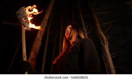 Young Lost Woman With Long Hair Standing In Forest At Night With A Handmade Torch