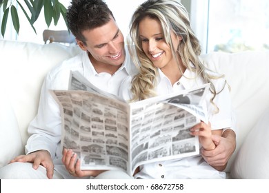 Young Love Couple Reading A Magazine  At Home